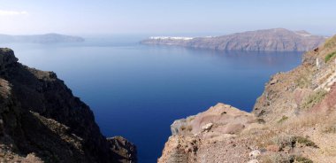 Yunanistan 'ın Santorini adasındaki Fira kasabasından dağların, denizin ve doğanın panoramik manzarası. Kalderanın ve körfezdeki gemilerin görüntüsü..