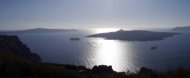 Yunanistan 'ın Santorini adasındaki Fira kasabasından dağların, denizin ve doğanın panoramik manzarası. Kalderanın ve körfezdeki gemilerin görüntüsü..