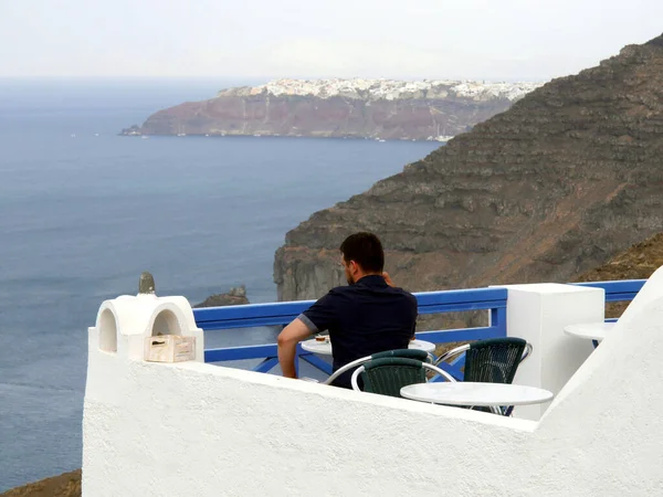 Turistler, Yunanistan 'ın Fira Santorini adasındaki geleneksel Yunan tavernasında öğle yemeği yiyor.