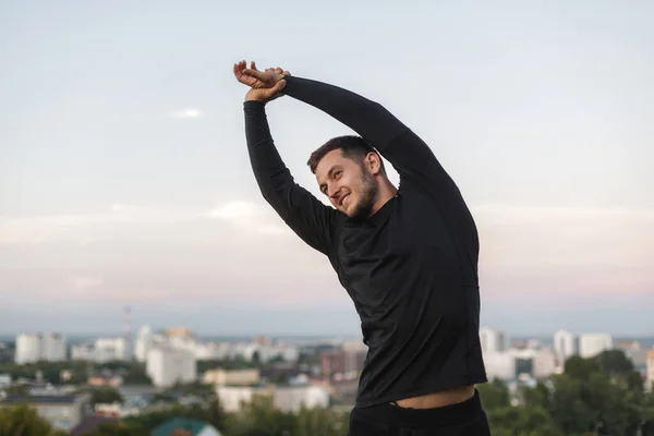 Image of healthy man stretching his body at sports ground outdoors