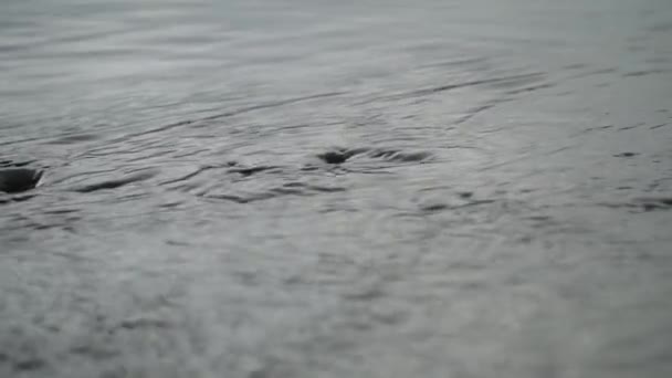 一条大河的波浪缓缓漂流 雨天水面上的门槛 石头和波纹 在雨中在桥上钓鱼 — 图库视频影像