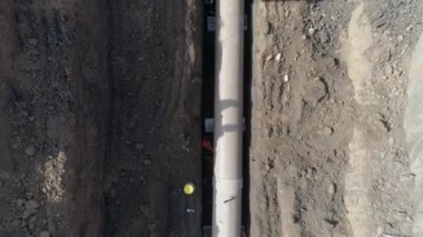 Beton boru tesisatı. Dışarıdaki adamların üzerindeki hava, kazma topraklarına su veya kanalizasyon boru hattı bağlamak ve kurmak için ağır makinelerle çalışıyor.