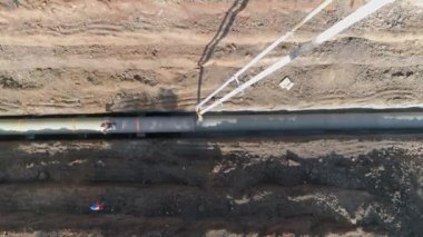 Boru hattının altyapısına beton döken büyük beyaz vinç üzerinde tepeden aşağı uçan drone görüntüsü. İnşaat alanında çalışan erkekler olarak.