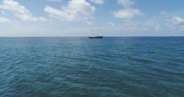 Mavi açık deniz suyundaki lüks yat teknesine hava aracı yaklaşımı. Alçak irtifa uçuşu