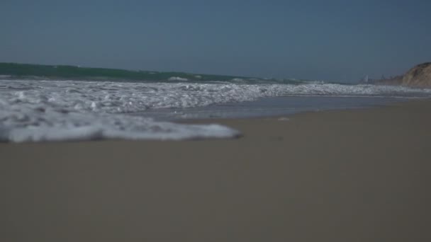 Vista de ángulo bajo y toma de cámara lenta de la orilla del mar con olas y espuma marina. — Vídeo de stock