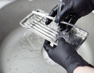 Bir dişçi doktoru elinde kauçuk bir baraj tutuyor. Tıbbi alet depolama dolabı. Dolap kayıyor.