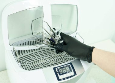 Bir dişçi doktoru elinde kauçuk bir baraj tutuyor. Tıbbi alet depolama dolabı. Dolap kayıyor.