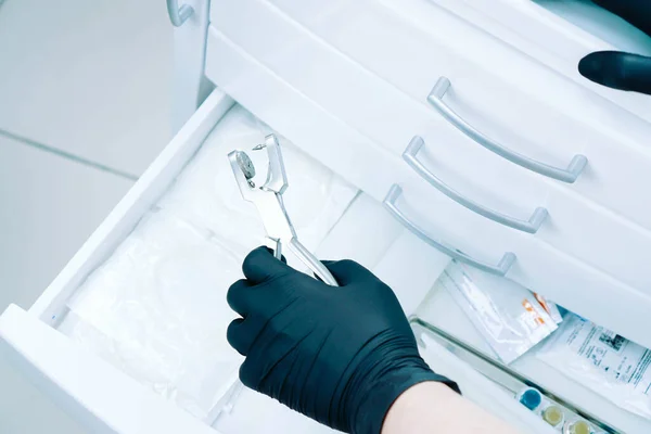 A dentist doctor holds a rubber dam in his hand. Medical tool storage cabinet. Sliding wardrobes