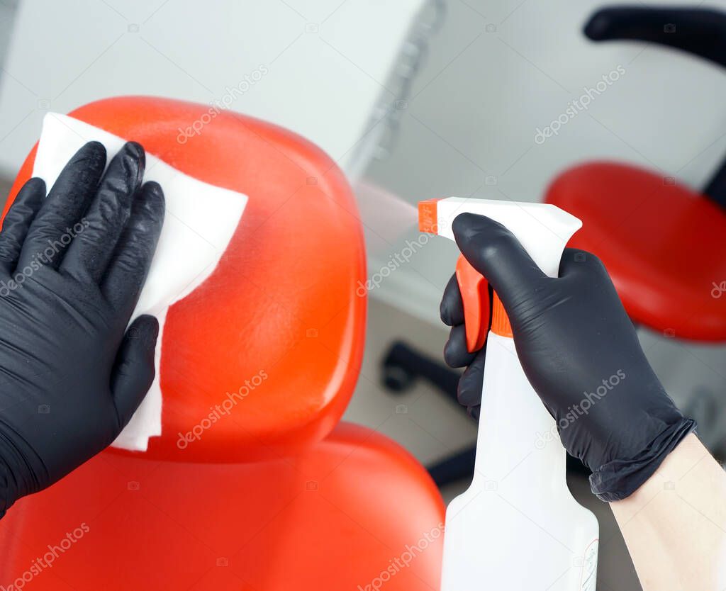 A dentist doctor holds a rubber dam in his hand. Medical tool storage cabinet. Sliding wardrobes