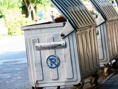 Bir şehir caddesinde gümüş renkli konteynırlar.