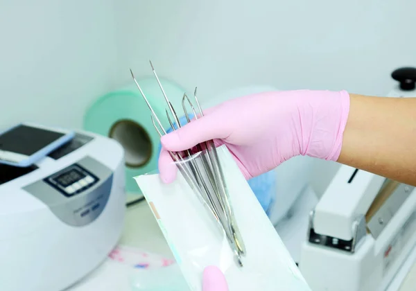 Dental instrument packaging in a sterilization bag. A medical worker puts a medical instrument in a device for disinfection and cleaning of germs. Stylishness and cleanliness in dentistry and medical facility, hospital, operating room.