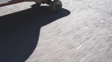 Genç patenci kaykaya biniyor ve numaralar yapıyor. Yavaş çekim kaykaycı güneşli bir günde açık havada..