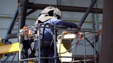 Koruyucu maskeli ve takım elbiseli profesyonel ağır endüstri işçisi fabrikada metal yapımında çalışıyor. Çelik ve demir kaynaklama şantiyesi. İş için ekipman hazırlığında kaynak.