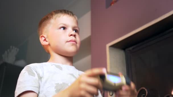 家庭でビデオゲームをプレイするための集中的な子供の学習 小さな男の子手でコンピュータゲームコントローラを保持し コンソールの屋内を再生します 集中的かつ関与する表情 — ストック動画