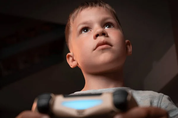 专注于儿童在家学习玩电子游戏 小男孩手握电脑游戏控制器 在室内玩控制台游戏 面部表情的聚焦及参与 — 图库照片