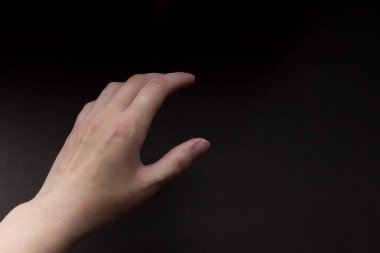 Kahverengi arka planda bir kadın eli. Kapatın. Boyut gösterme hareketi