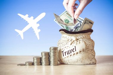 El çantasına Amerikan dolarları, masaya bozuk paralar, arka planda uçağın silüeti olan bozuk para koy. Para biriktirme kavramı. Yatırım fikirleri, gelecek için finansal yönetim. İş Büyüme Konsepti