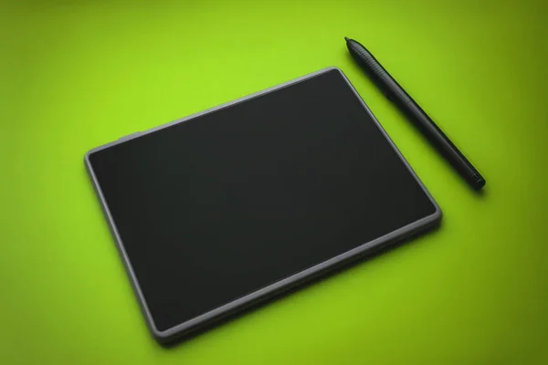 Graphic tablet pen on the surface of the device, close-up photo. graphic tablet with pen for illustrators and designers, on green background