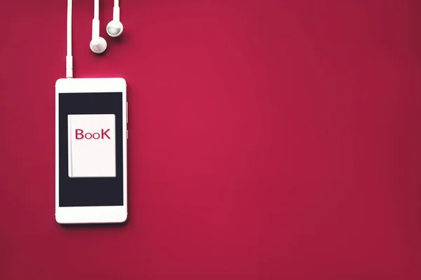Kulaklıklı yaratıcı cep telefonu ve kırmızı arka planda Audiobook. Ses, dinle. Audiobook konsepti