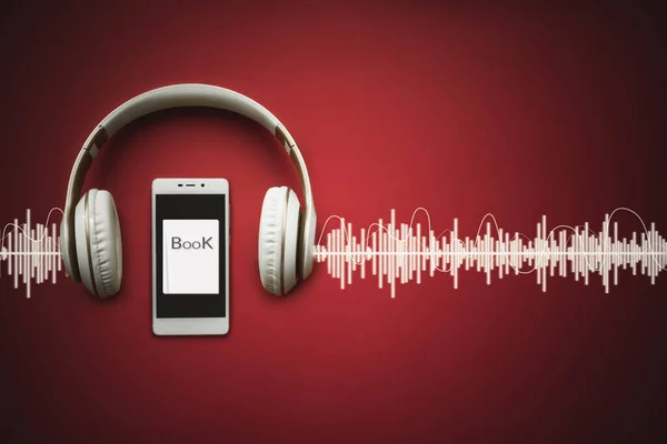 Akıllı telefonların, kulaklıkların ve Audiobook 'un kırmızı arka planda ses kaydının olduğu yakın plan çekimleri. Ses, dinle. Audiobook konsepti