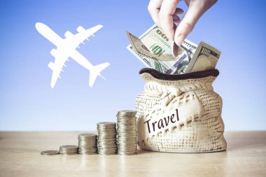 Çantanın içinde Amerikan Doları banknotları. Masada bozuk paralar var. Arka planda uçağın silüeti var. Seyahatten tasarruf kavramı. Yatırım fikirleri, gelecek için finansal yönetim. İş Büyüme Konsepti