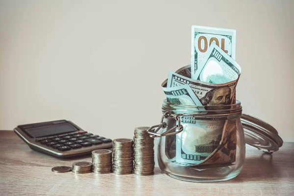 Bozuk paralar, hesap makinesi ve kavanozdaki Amerikan dolarları. Tasarruf kavramı, mali. Gelecek için para ve gelir tasarrufu yatırım fikirleri ve mali yönetim. Kapatın. İş büyümesi konsepti. Mali risk