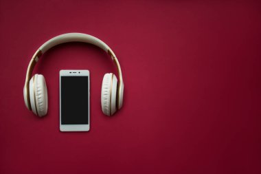 Kırmızı arka planda akıllı telefon modeli. Düz yatıyordu. Uzayı kopyala Müzik konsepti. Üst görünüm