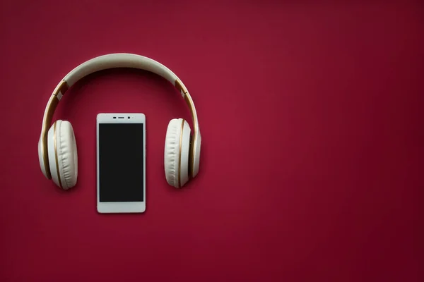 Kırmızı arka planda akıllı telefon modeli. Düz yatıyordu. Uzayı kopyala Müzik konsepti. Üst görünüm