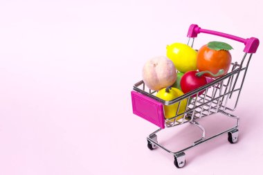 Rengarenk meyve ve sebze çeşitleriyle dolu oyuncak minyatür alışveriş arabası.
