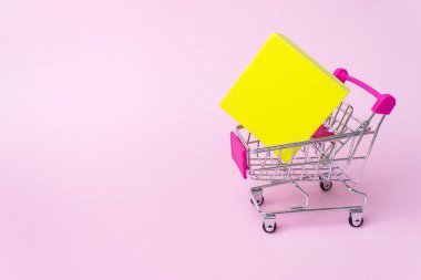 Alışveriş, alışverişler, süpermarket, satış, alışveriş merkezi konsepti. Oyuncak metal alışveriş arabasını kapayın. Pembe arka planda elf kutusu olsun. Markette büyük indirim var. Bakkaliye için en iyi fiyat