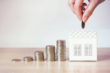 İnsanların eli, küçük evi ve parası, ev bankacılığı ve tasarruf konsepti. Fikir Evi finansmanı, tasarruf ve emlak yatırımları konsepti