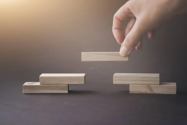Tahta bloklar kahverengi arka planda piramit merdiveni olarak diziliyor. İş organizasyonu başlangıç konsepti