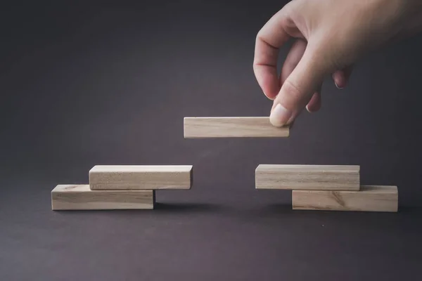 El, tahta bloklardan bir merdiveni katlar. Başarı, büyüme, kazanç, zafer, kalkınma veya en üst düzey konsept