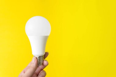 Sarı arka planda bir ampul var. Yeni enerji teknolojisi. Boşluğu kopyala