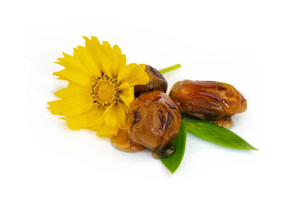 Dates with green leaves under syrup on white background