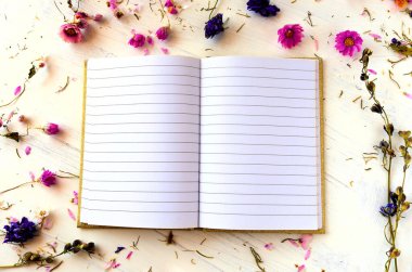 Kurumuş çiçeklerin arka planında güzel bir defter. Romantik ve boho tarzı. Çok kadınsı bir fotoğraf..