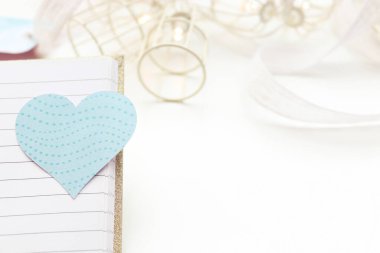 Turkuaz kalp. Arka planda ışıklar olan bir defter ve beyaz arkaplan aç.