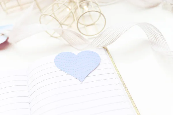 Turquoise heart. Open notebook and white background with lights in the background.