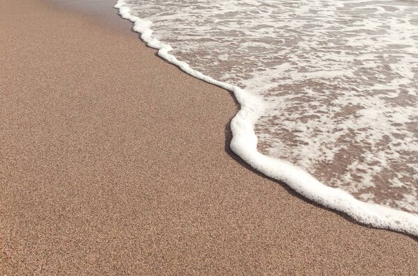 Wave retreating in brown sand. Summer landscape. Mediterranean sea. Catalonia. Spain.