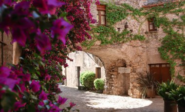 Duvarlarında çiçekler olan bir kasabada ortaçağ sokakları. Bir Avrupa ve Akdeniz kasabasının resmi. Peratallada. İspanya 'da görülecek şeyler. Catalua 'da ne görüyorsun?.