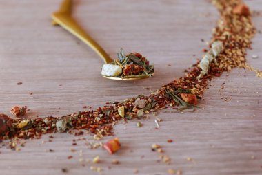 Tahta masanın üzerinde çay çemberinin yanında altın kaşık. Sıcak renkler. Yeşil, turuncu, altın. Çay zamanı. Metnin için boşluk