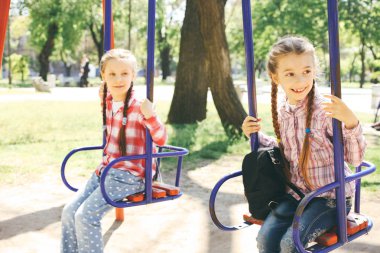 Parkta bir salıncak üzerinde sallanan iki kız arkadaşım.