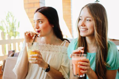 İki güzel kızın taze meyve smoothies bir kafede içiyorsun.