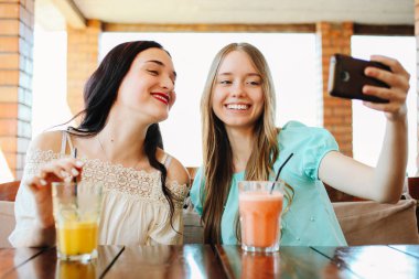 İki güzel kızın taze meyve smoothies bir kafede içiyorsun.