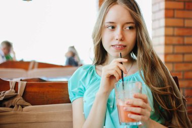 Güzel bir kız bir kafede taze meyve smoothies içiyor.