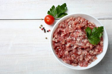 Baharat ve domates ahşap arka plan üzerinde beyaz bir kase kıyılmış et. Üstten görünüm, kopya alanı. 