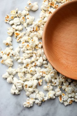 Patlamış mısır ve mermer bir zemin üzerine boş bir derin kase tuzlu.