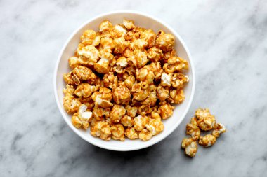 Mermer bir zemin üzerine beyaz bir derin kapta tatlı karamelli patlamış mısır.