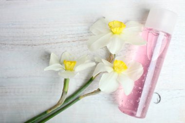 Pembe duş jeli ve nergis ahşap arka plan üzerinde. Üstten görünüm.