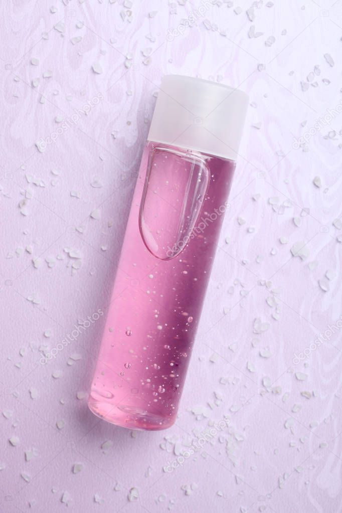One pink shower gel and sea salt on a purple background.